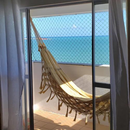 a hammock in a room with a view of the ocean at Apartamento Beira Mar in Maceió