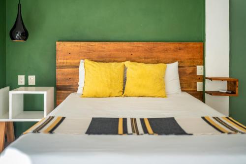 a bed with yellow pillows and a green wall at Sayula HoME in Sayulita