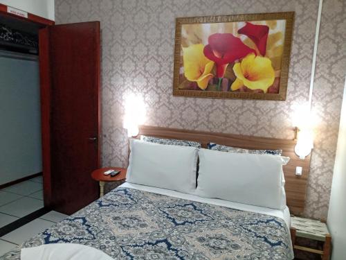 a bedroom with a bed and a painting on the wall at Hospedagem Da Laranjeira Gramado in Gramado
