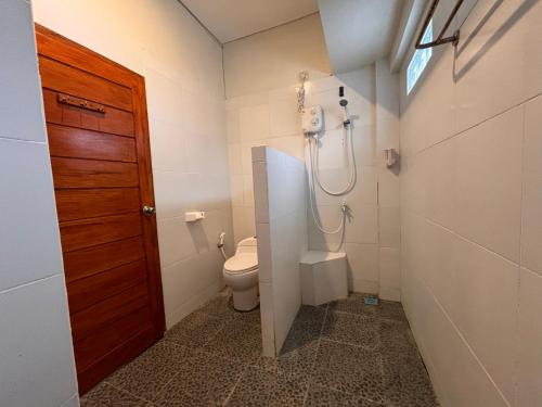 a bathroom with a toilet and a shower at MAI LAKU Cottage in Sekotong