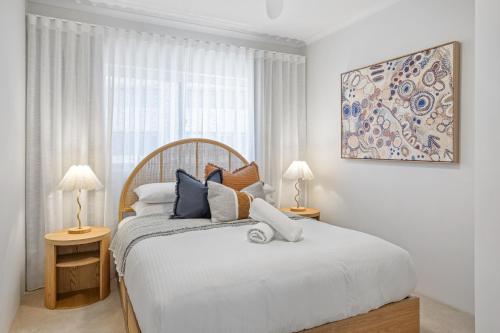 a white bedroom with a large bed and two lamps at Stylish 3-Bed Apartment in Coastal Redcliffe in Redcliffe
