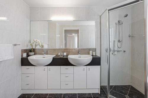 a white bathroom with two sinks and a shower at Stylish 3-Bed Apartment in Coastal Redcliffe in Redcliffe