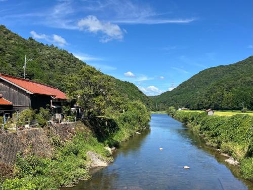 a river in a valley with a building and mountains at 古月(KozukI)久年庵 in Yamaguchi