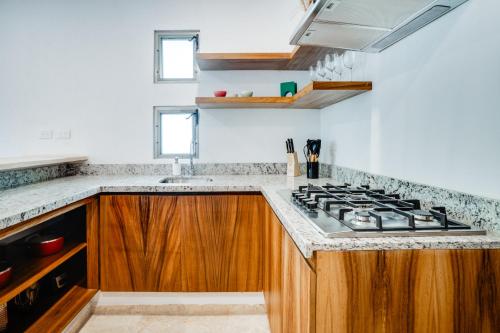 a kitchen with a stove top and wooden cabinets at Casa Manglar Riviera Maya in Puerto Aventuras