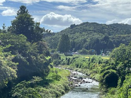 a river with trees and a mountain in the background at 古月(KozukI)久年庵 in Yamaguchi