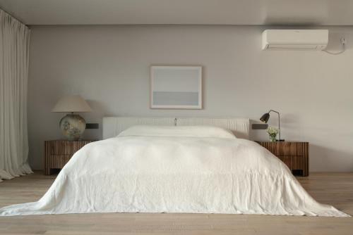 1 dormitorio blanco con 1 cama blanca grande con sábanas blancas en Dali Xishang Shuanglang Hotel, en Dali Shuanglang