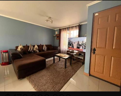 a living room with a brown couch and a tv at Casa Disponible in Talcahuano