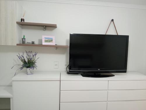 a flat screen tv sitting on top of a white dresser at LOFT NOVO CONFORTÁVEL in Sorocaba