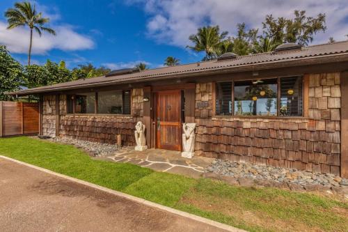 a stone house with a wooden door and grass at Hale Maluhia Hanalei home in Hanalei