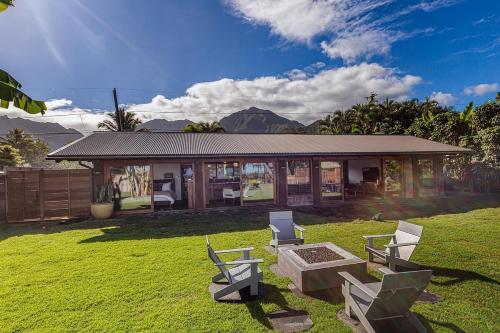 a house with two chairs and a table in the grass at Hale Maluhia Hanalei home in Hanalei