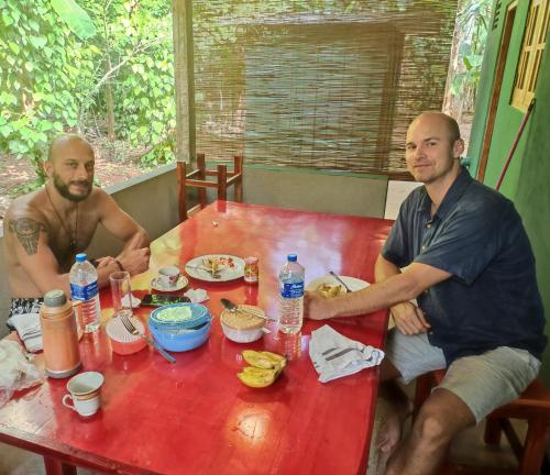 Dois homens sentados à mesa a comer. em Gaya Family Resort em Udawalawe