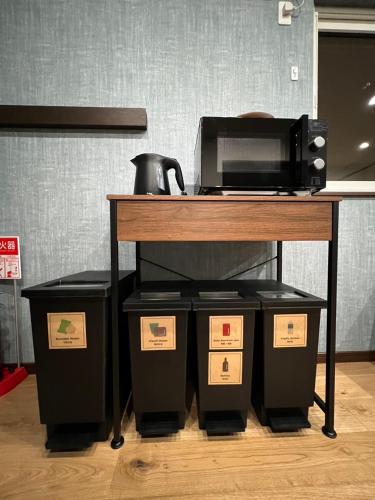 a table with a microwave and four trash cans under it at Go Home 豪 in Furano