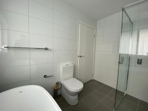 a bathroom with a toilet and a glass shower at Luxury 4 Bedroom Home - Sleeps 10 Guests in Gledswood Hills