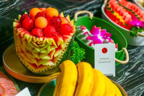 a table with a cake with fruit on it and bananas at Aurora Central Hanoi Hotel in Hanoi