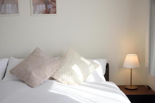 a white bed with white pillows and a lamp at Villa RIKUNOYA SUZUKA in Suzuka