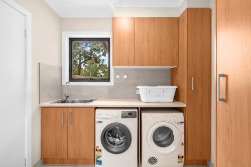 a kitchen with a washing machine and a sink at Bungunyah Apartments in Croydon