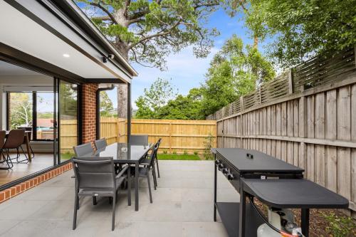 a patio with a table and chairs and a fence at Bungunyah Apartments in Croydon