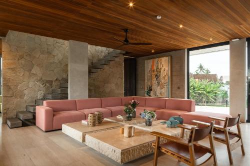 a living room with a pink couch and a table at Villa Famara Pererenan, Canggu by Blacksand in Tumbak Bayuh