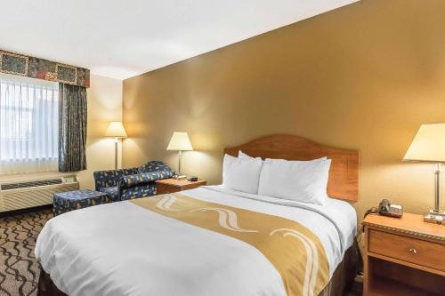 a hotel room with a bed and a chair at Quality Inn Charleston - Sikeston in Charleston