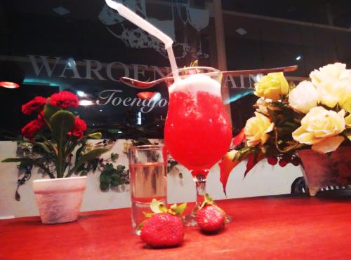 a drink in a glass sitting on a table with strawberries at Varna Culture Hotel Soerabaia in Surabaya