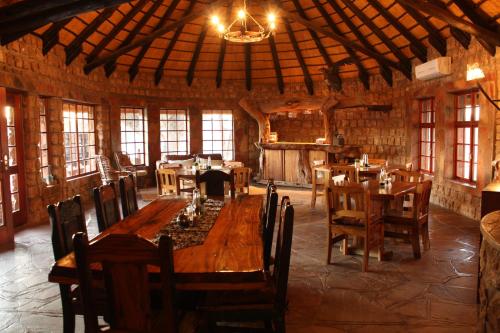 uma sala de jantar com uma grande mesa de madeira e cadeiras em Torgos Lodge em Koës