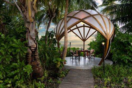 a table and chairs under an umbrella in a garden at Niyama Private Islands Maldives in Dhaalu Atoll