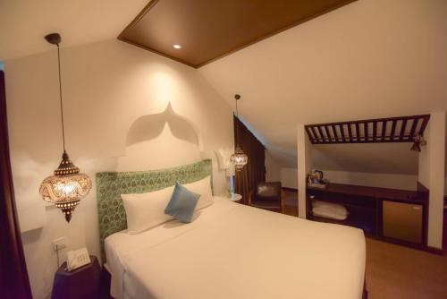 a bedroom with a white bed with a chandelier at Rosa Hanoi Hotel in Hanoi