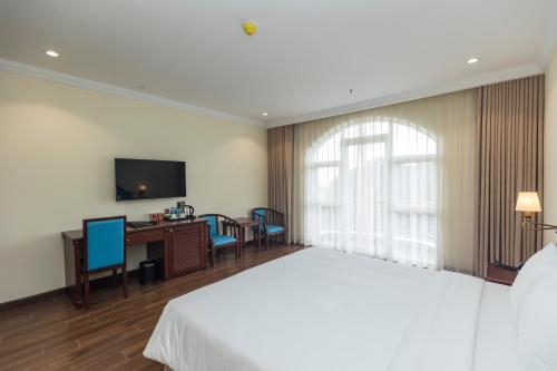 a bedroom with a bed and a desk and a television at CALYSSA HOTELS & VILLAGE in Khu Chi Lăng