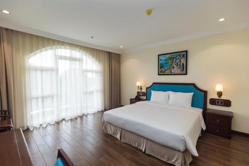 a bedroom with a large bed and a large window at CALYSSA HOTELS & VILLAGE in Khu Chi Lăng