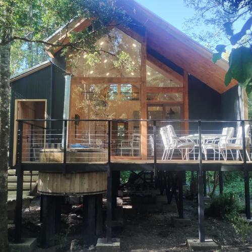 a cabin in the woods with chairs on a deck at Cabaña en molco,entre Villarrica y Pucón in Molco
