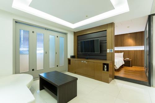 a living room with a television and a bed at Browndot Hotel Incheon Songdo in Incheon
