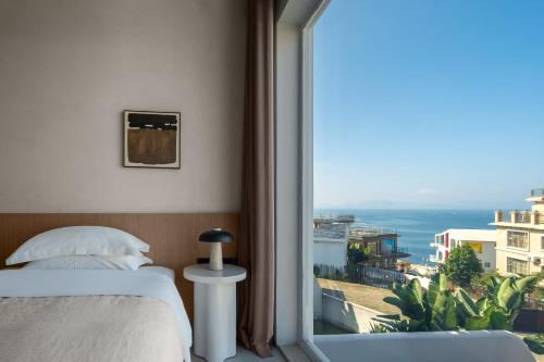 a bedroom with a bed and a view of the ocean at Miyue Shenzhen Blue and White Holy Island Cliff Pool Hotel in Shenzhen