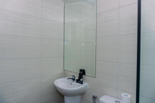 a white bathroom with a sink and a mirror at Modern Look 1BR at 22nd Floor Ciputra International Apartment By Travelio in Jakarta