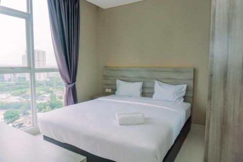 a bedroom with a large white bed with a window at Modern Look 1BR at 22nd Floor Ciputra International Apartment By Travelio in Jakarta