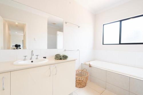 Un baño blanco con lavabo y bañera. en The Beachwood Nest, en Cable Beach