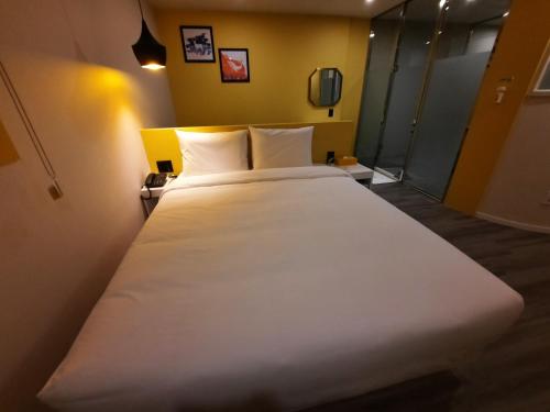 a large white bed in a room with yellow walls at Rein Hotel Busan Yeonsan in Busan