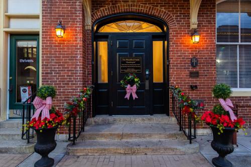 a black door with flowers in front of a brick building at The Woodford Hotel in Versailles