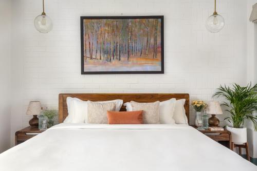 a bedroom with a white bed and a painting on the wall at La Olalian 2 & 3 BHK Designer Villas Near Anjuna Beach with Private Pool & Sun Deck & Garden in Anjuna