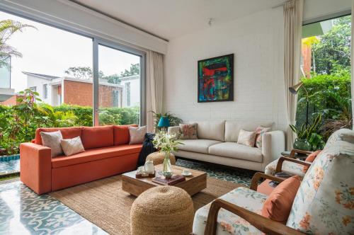 a living room with orange furniture and a large window at La Olalian 2 & 3 BHK Designer Villas Near Anjuna Beach with Private Pool & Sun Deck & Garden in Anjuna