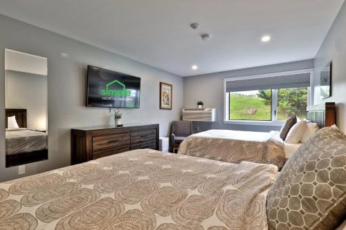 a bedroom with two beds and a flat screen tv at Ski Condo Close to the Resort, Shuttle Bus Route, Summer Pool, 2 Queen Beds in Killington