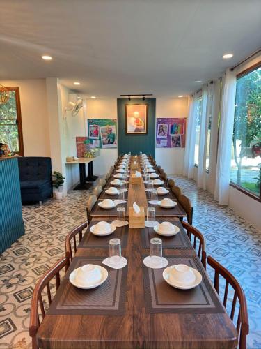 a long long table in a room with chairs at บ้านริมเนิน รีสอร์ท งาว in Ngao