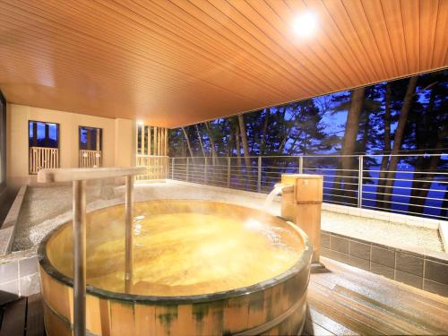 a large wooden tub in a room with a large window at Hamabeno Ryouriyado Houraikan in Kamaishi