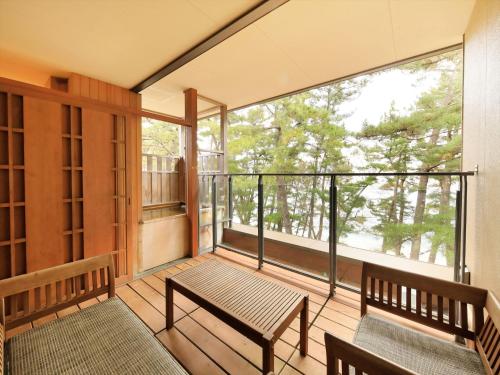 a balcony with two benches and a large window at Hamabeno Ryouriyado Houraikan in Kamaishi