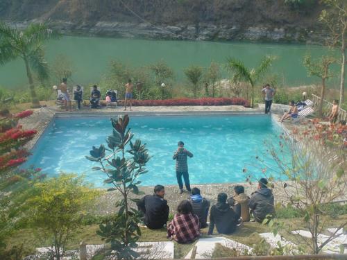un grupo de personas sentadas alrededor de una piscina en River Fun Beach Resort, en Gorkhā