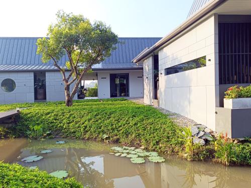 a house with a pond in front of a building at Chombua MaeWang ชมบัว in Chiang Mai