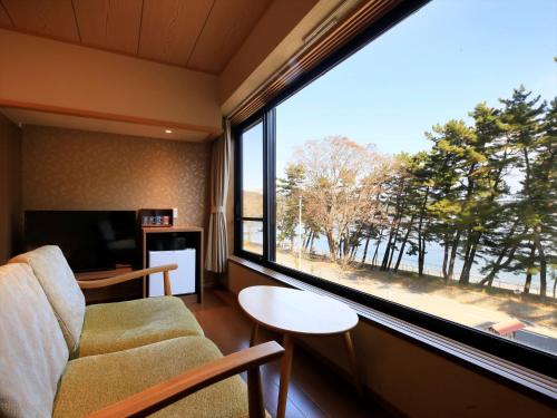 a living room with a couch and a large window at Hamabeno Ryouriyado Houraikan in Kamaishi