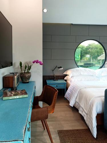 a bedroom with a bed and a desk and a window at Chombua MaeWang ชมบัว in Chiang Mai