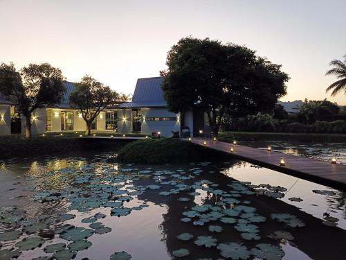 a house with a pond of water lilies at Chombua MaeWang ชมบัว in Chiang Mai