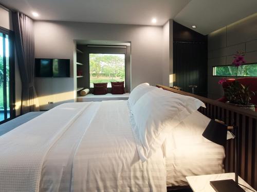 a large white bed in a room with a window at Chombua MaeWang ชมบัว in Chiang Mai