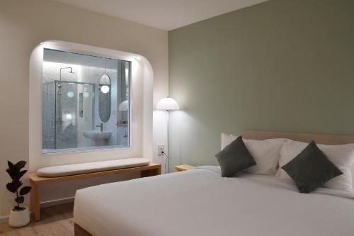 a bedroom with a large white bed and a mirror at Squirrel House in Bang Rak